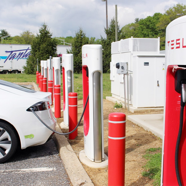 A Tesla electric vehicle charges at a row of existing chargers at the John Fenwick Service Area on the New Jersey Turnpike.