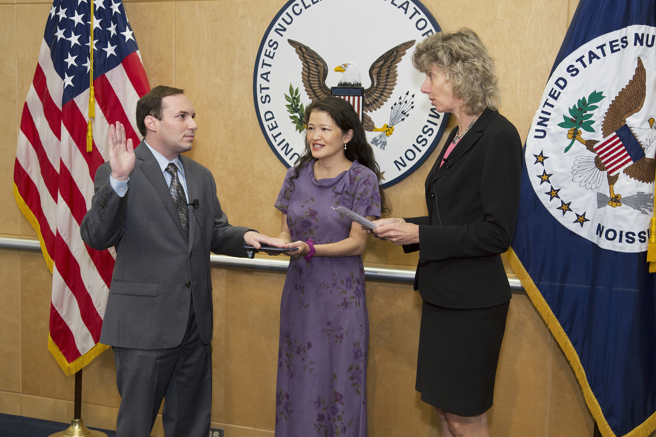 Jeff Baran is sworn in as a  NRC commissioner by Chairman Allison M. Macfarlane (right) as his wife Michelle Yau looks on. (Source: NRC)